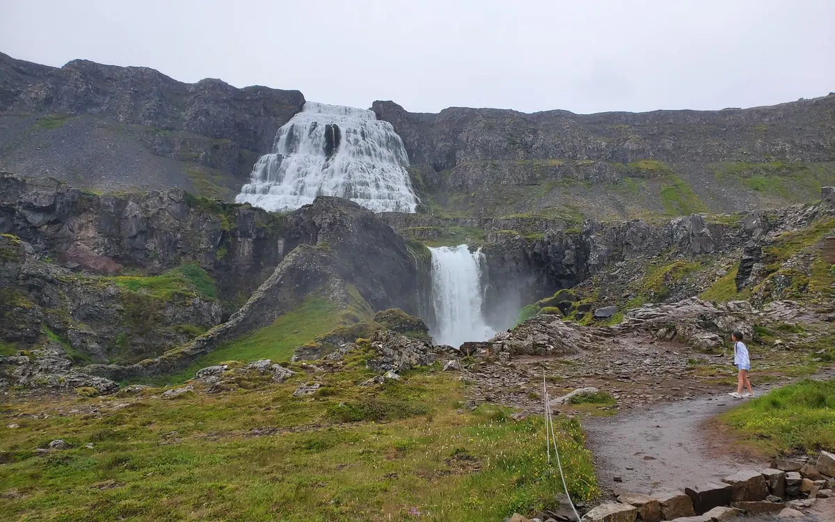 The tiered Dynjandi waterfall above a smaller fall, with a gravel path leading towards it