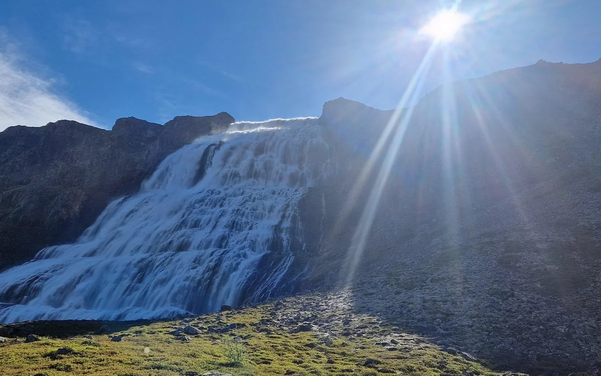 Dynjandi waterfall with the sun flaring over the ridge above it
